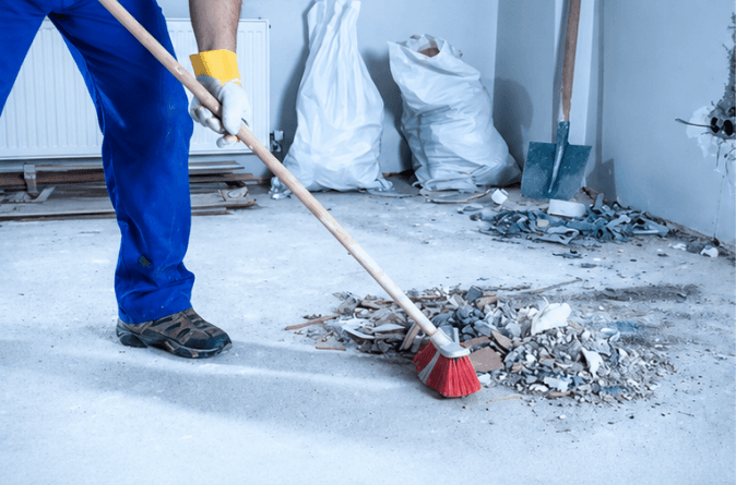 Agent balayant des gravats sur un chantier en fin de travaux